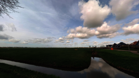 Een mooie foto van een weiland en een sloot. De blauwe lucht en wolken weerspiegelen in de sloot. 